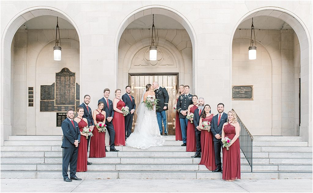full wedding party standing on the steps at citadel's summerall chapel red bridesmaids navy groomsmen