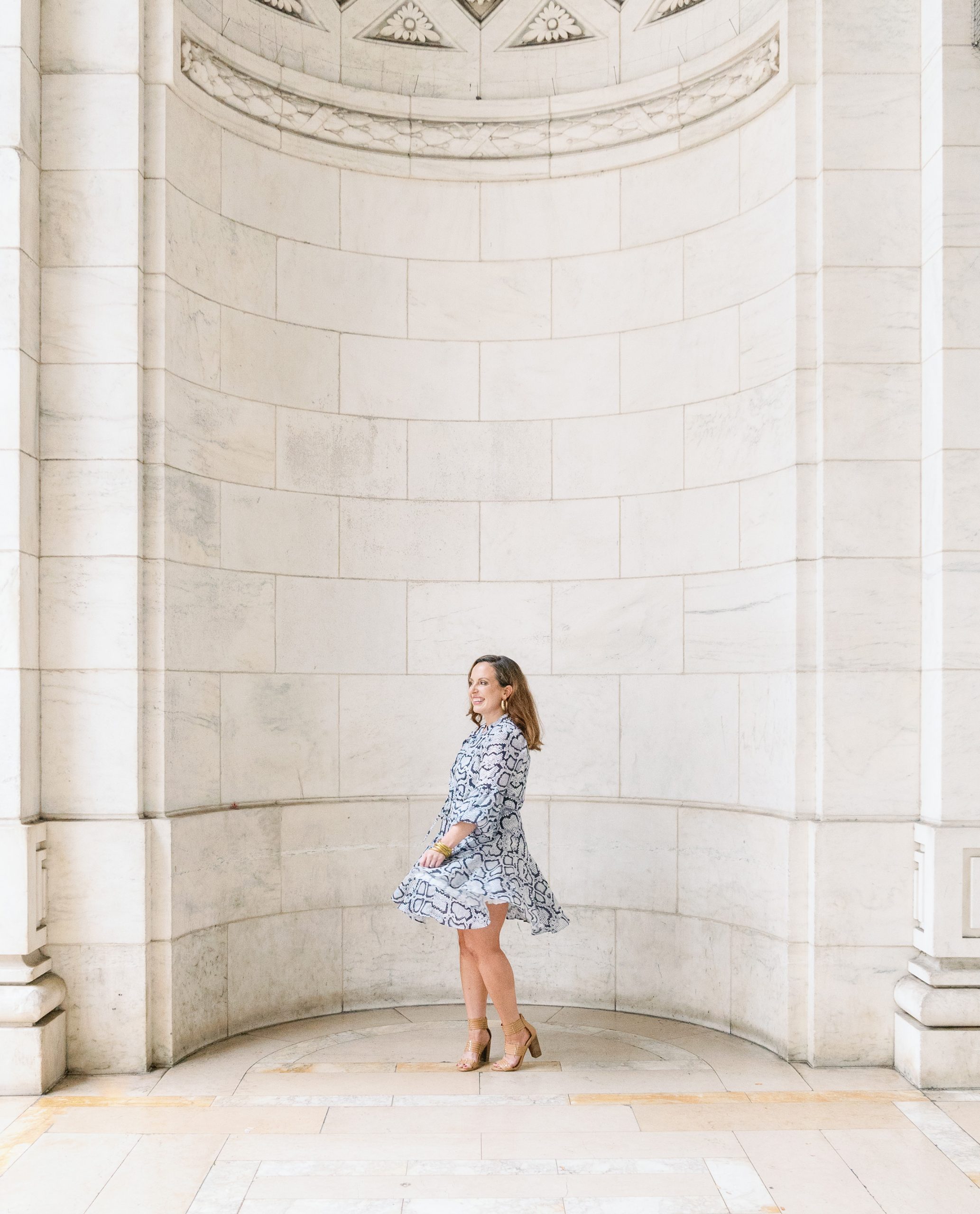 Melissa Brewer Photography twirling at New York City's public library in a green and white dress and laughing smile